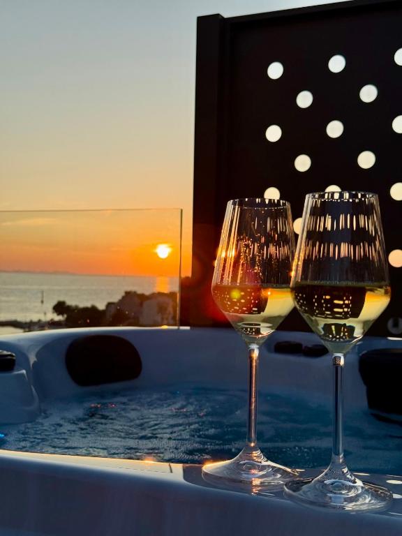 zwei Gläser Wein auf einem Tisch mit Sonnenuntergang in der Unterkunft Dedaj Resort - Penthouse Auri in Zadar