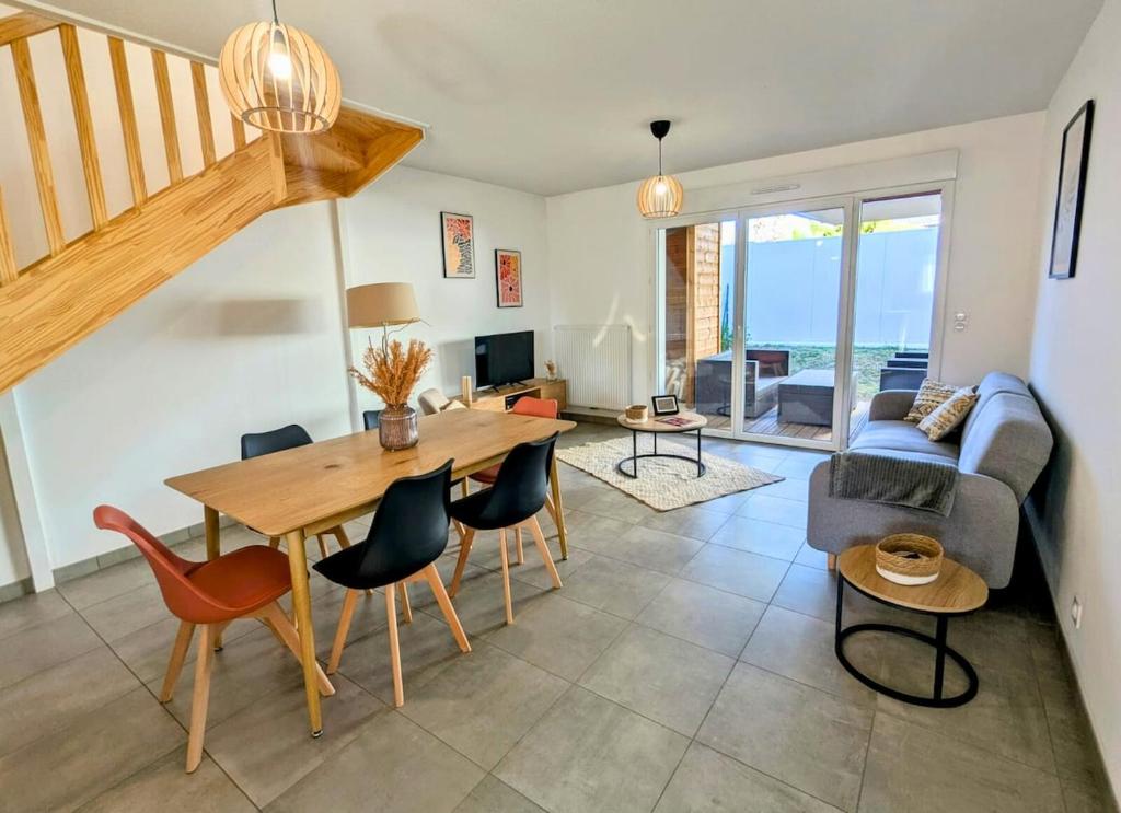 a living room with a table and chairs and a couch at Maison T4 jardin, garage, terrasse, bureau in Dax