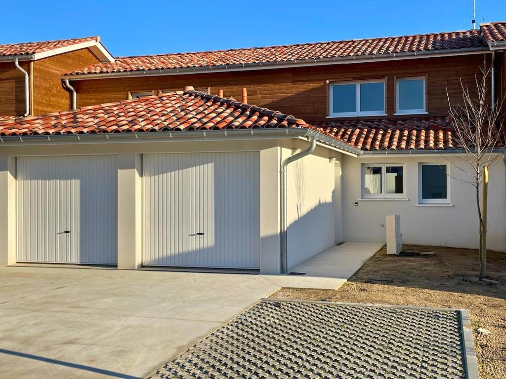 une maison avec deux portes de garage dans une allée dans l'établissement Maison T4 jardin, garage, terrasse, bureau, à Dax