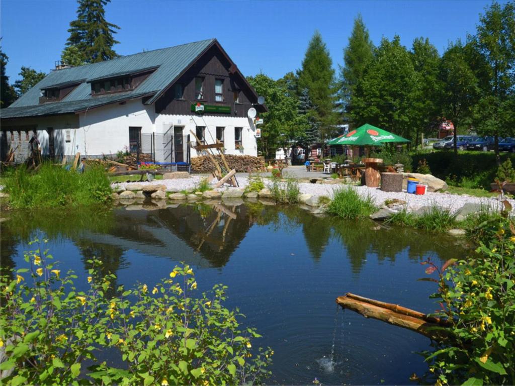 ハルラホフにあるPenzion & Restaurant Pod Čerťákemの池を前に建つ建物