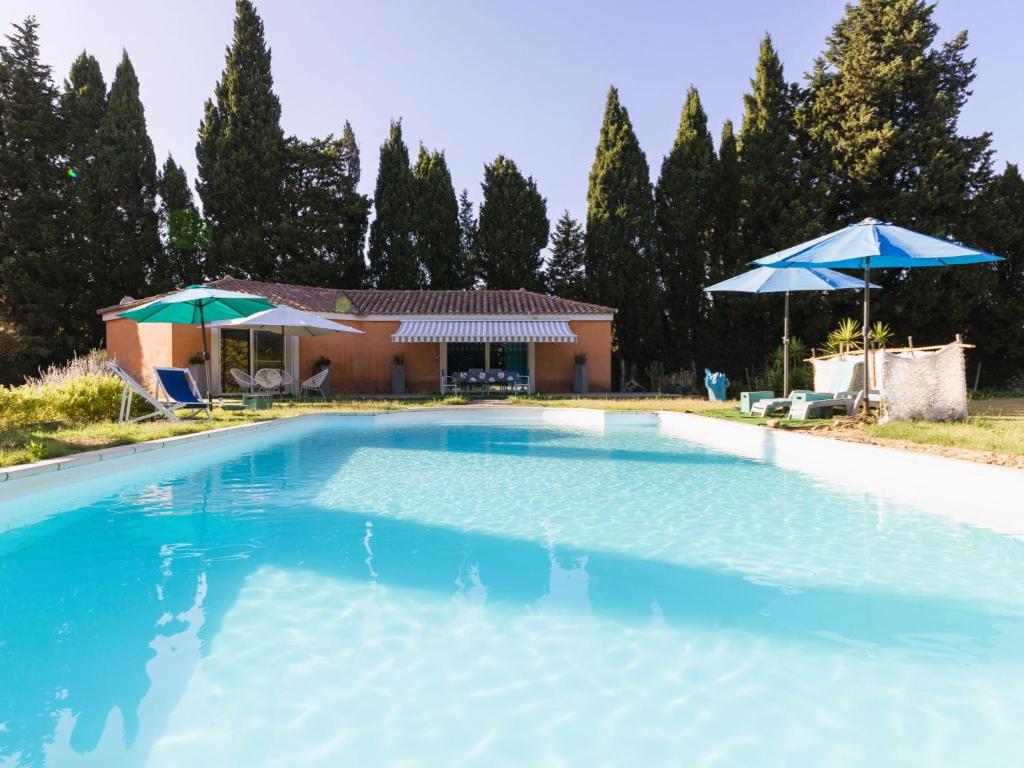 - une piscine en face d'une maison avec des parasols dans l'établissement Holiday Home Un petit coin de paradis by Interhome, à Châteaurenard