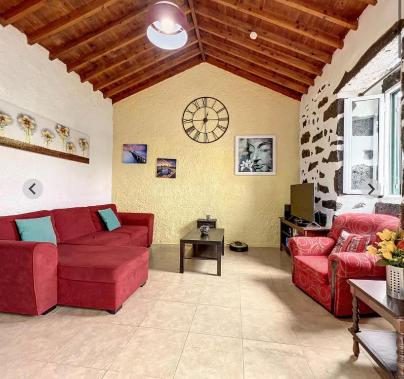 ein Wohnzimmer mit zwei roten Sofas und einem Tisch in der Unterkunft Northeast Azores, Rocha Mar House in Nordestinho