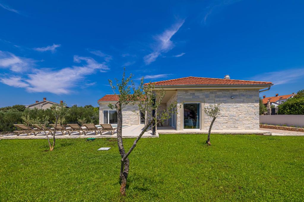a house with a green lawn with trees in the yard at Villa FUSKA with private pool in Pinezici