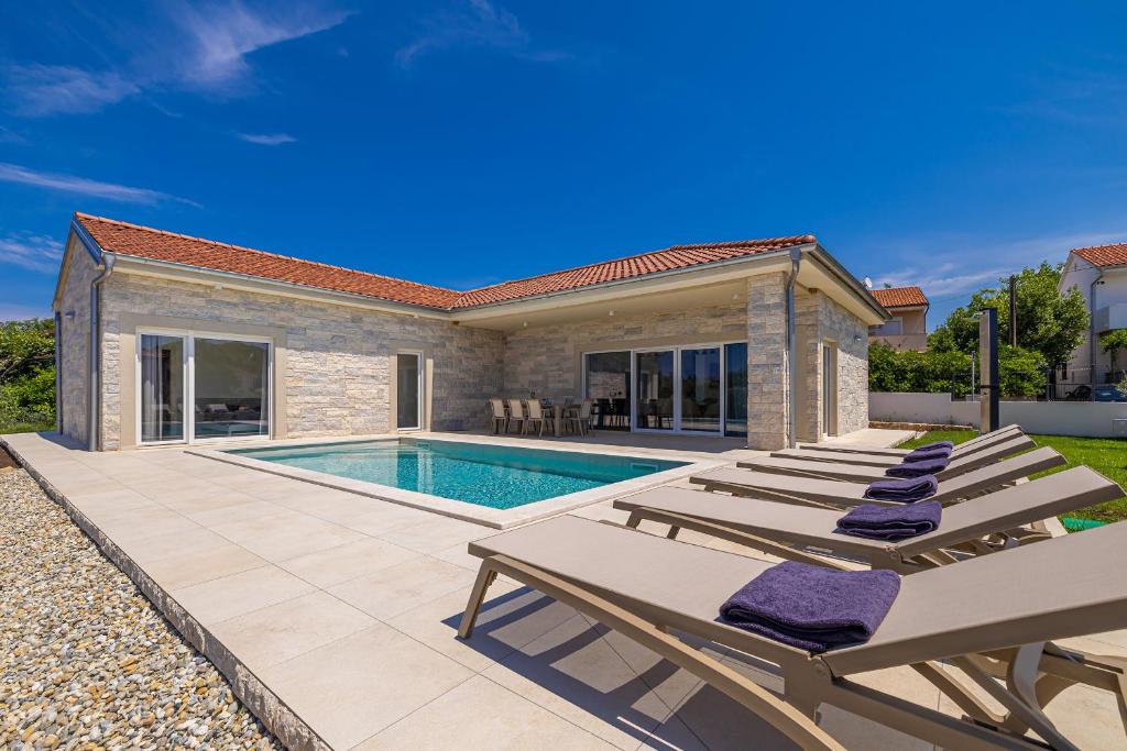 a villa with a swimming pool and two lounge chairs at Villa FUSKA with private pool in Pinezici