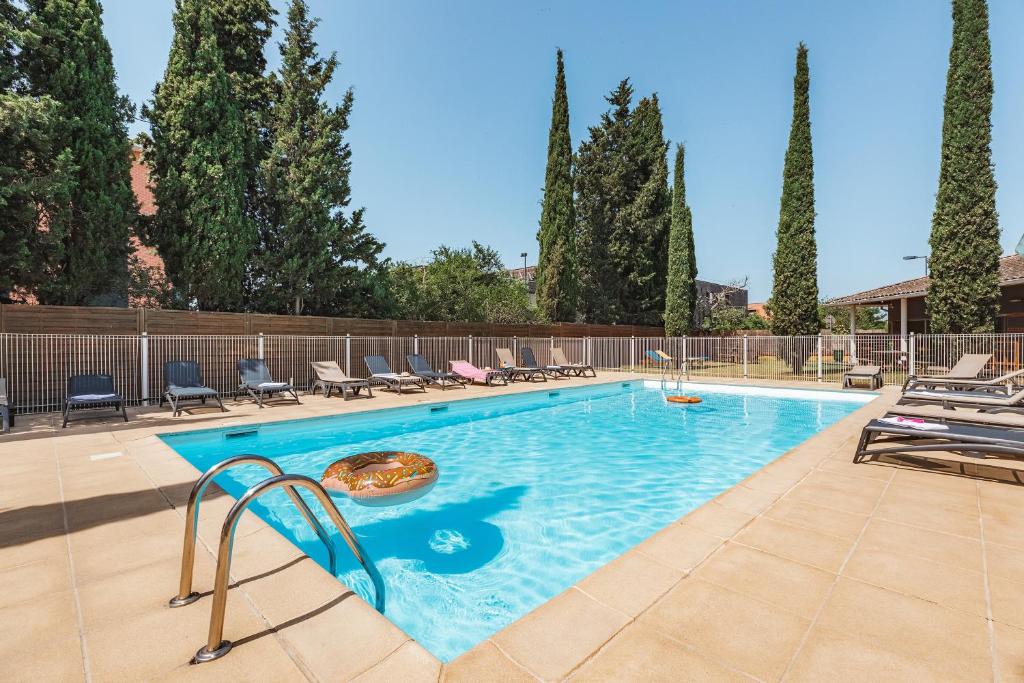 une piscine avec des chaises et une pizza au milieu dans l'établissement Appart'City Classic Toulouse Saint-Simon, à Toulouse
