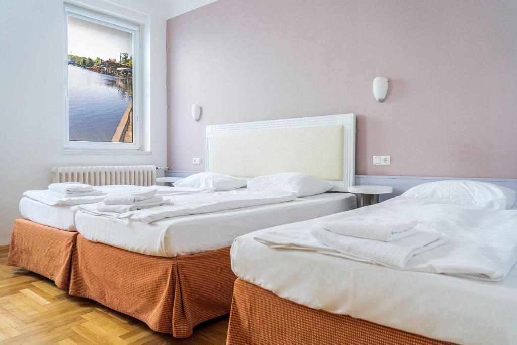 three beds in a room with a large window at Hotel Metro in Budapest