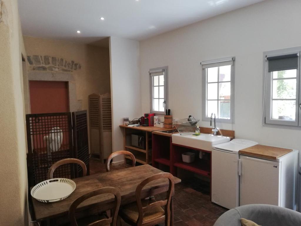 a kitchen with a wooden table and a kitchen with a sink at Les Tomettes in Dole