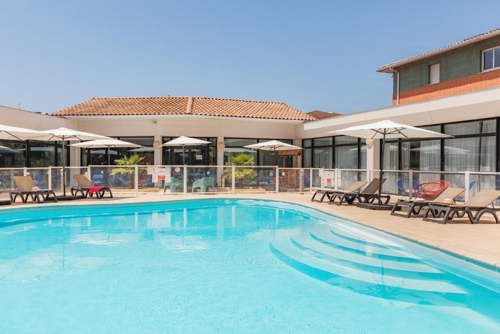 a large swimming pool with chairs and umbrellas at Appart'City Confort Toulouse Purpan in Toulouse