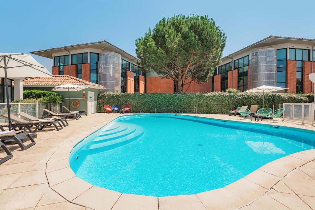 une piscine devant un immeuble dans l'établissement Appart'City Confort Toulouse Purpan, à Toulouse