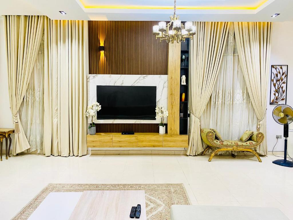 a living room with a large television and a chair at 3Apartments in Lagos