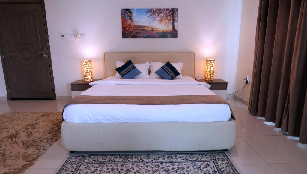 a bedroom with a large bed with two lamps at Royal Suites Muscat in Ma‘ābīlah