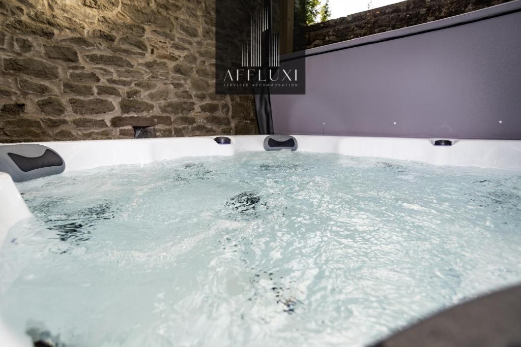 una vasca da bagno riempita d'acqua accanto a un muro di mattoni di Abergavenny Coach House Hot Tub Retreat a Monkswood