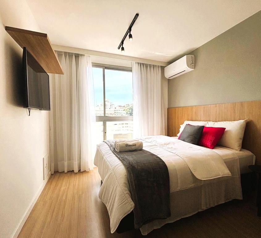 a bedroom with a bed and a large window at UniHome Niterói in Niterói