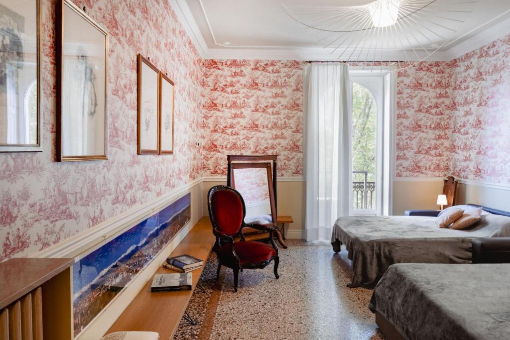 トリノにあるEleganza sabauda 120 sqm Luxury historical flatのピンクの壁紙と赤い椅子のある寝室