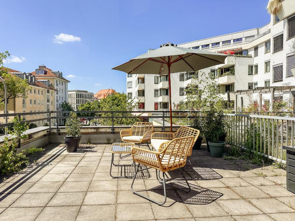 a patio with two chairs and an umbrella at MARAL Loft München Bogenhausen in Munich