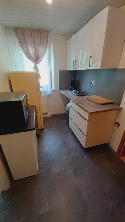 a kitchen with white cabinets and a large window at Einfache 2 Zimmer Wohnung mit Parkplatz nur 8 Min nach Bayreuth in Mistelgau