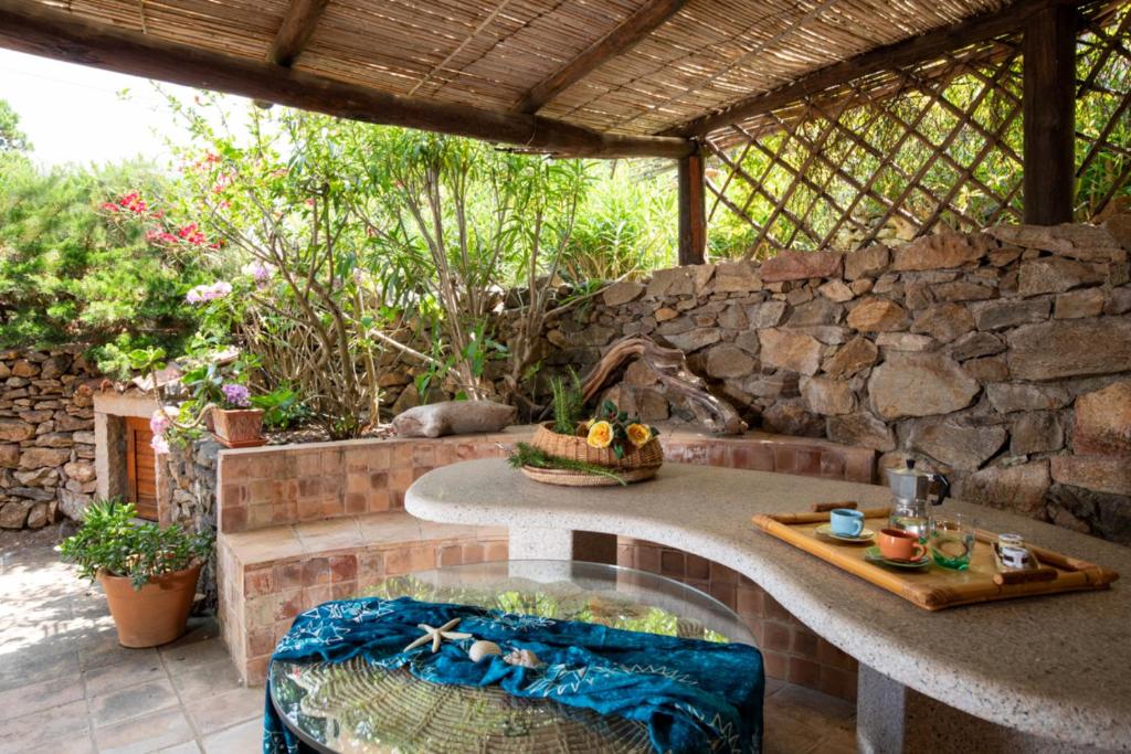 a patio with a table and a stone wall at Casa Irene by Wonderful Italy in Porto Cervo