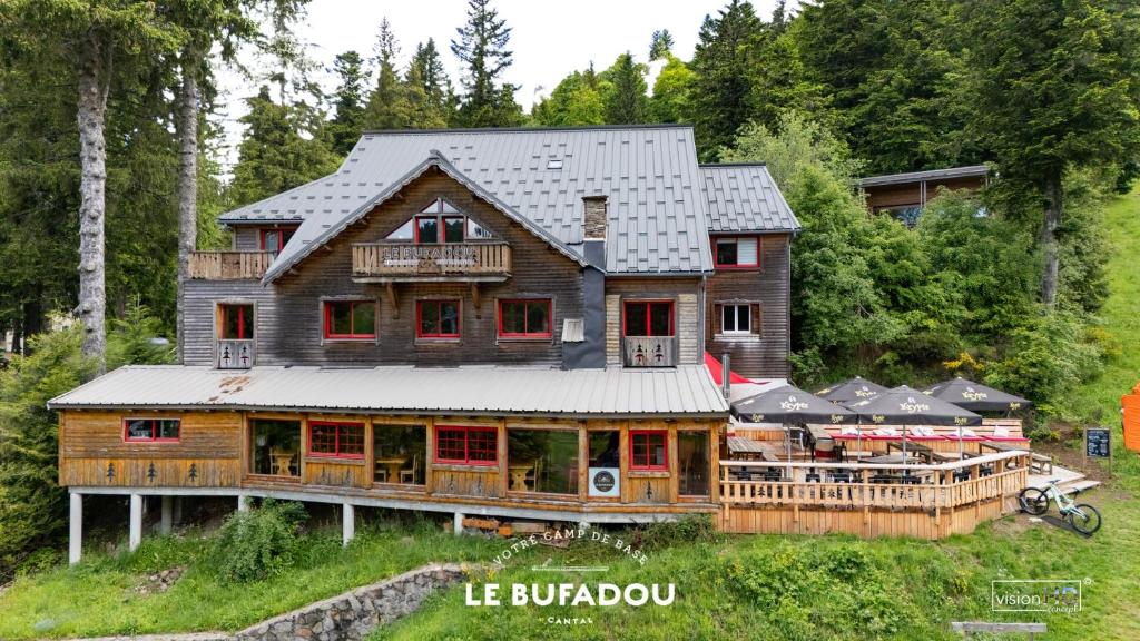 a large wooden house with a roof at LE BUFADOU - Gîte Auberge - in Laveissière