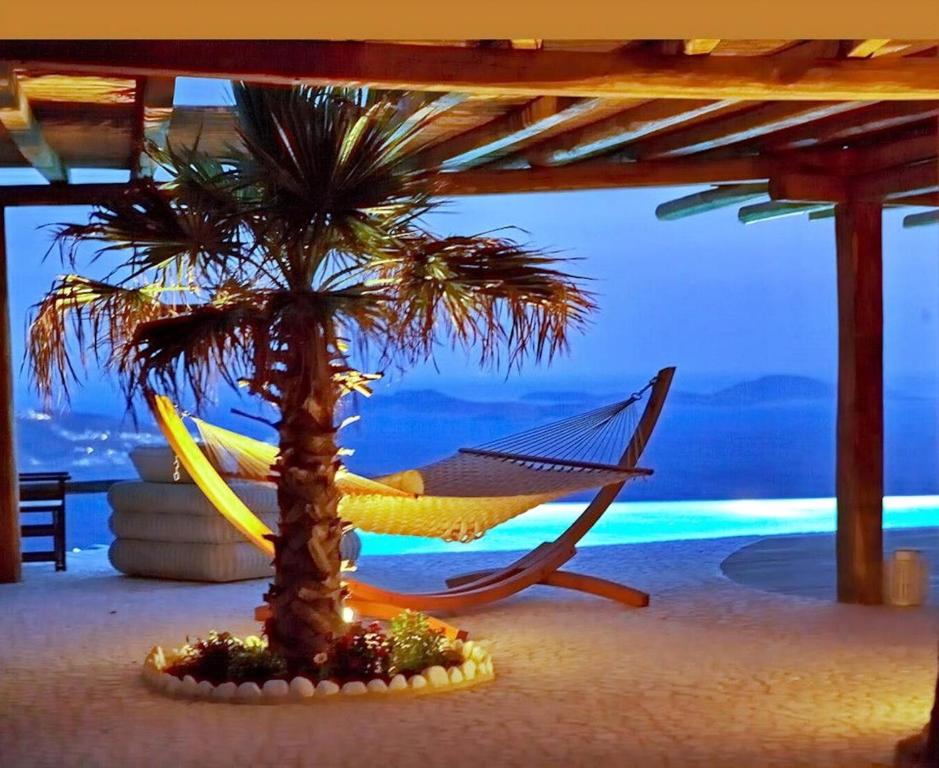 a hammock and a palm tree on a beach at Luxury Mykonos Villa Kings And Queens Villa Private Pool Kastro in Mýkonos City
