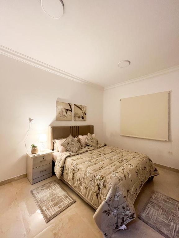 a white bedroom with a bed and a night stand at شقق راقية بأثاث حديث وراقي 1 in Dammam