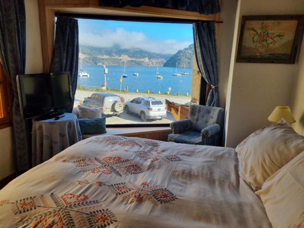 a bedroom with a bed and a window with a view of the water at CABAÑA LUGAR SOÑADO FRENTE al LAGO, unidades CON VISTA AL LAGO Y SIN vista al lago in San Martín de los Andes