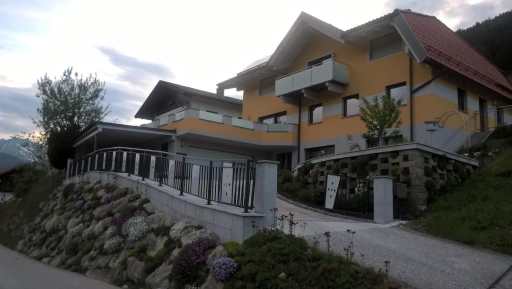 a large yellow house with a stone retaining wall at Gästehaus Alberta in Navis