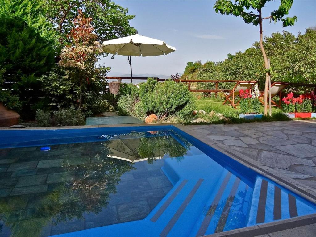 einen Pool mit Sonnenschirm im Hof in der Unterkunft Great Pelion Villa Villa Dioni 2 Bedrooms Aghios Georgios in Pilion