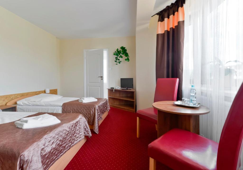 a hotel room with two beds and a table and chairs at Harmonia in Biała Podlaska