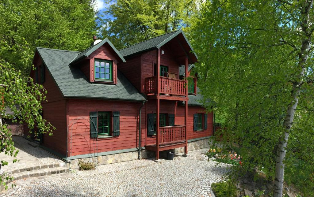 een rood huis met een balkon in het bos bij Bukowy Zdrój in Krynica Zdrój