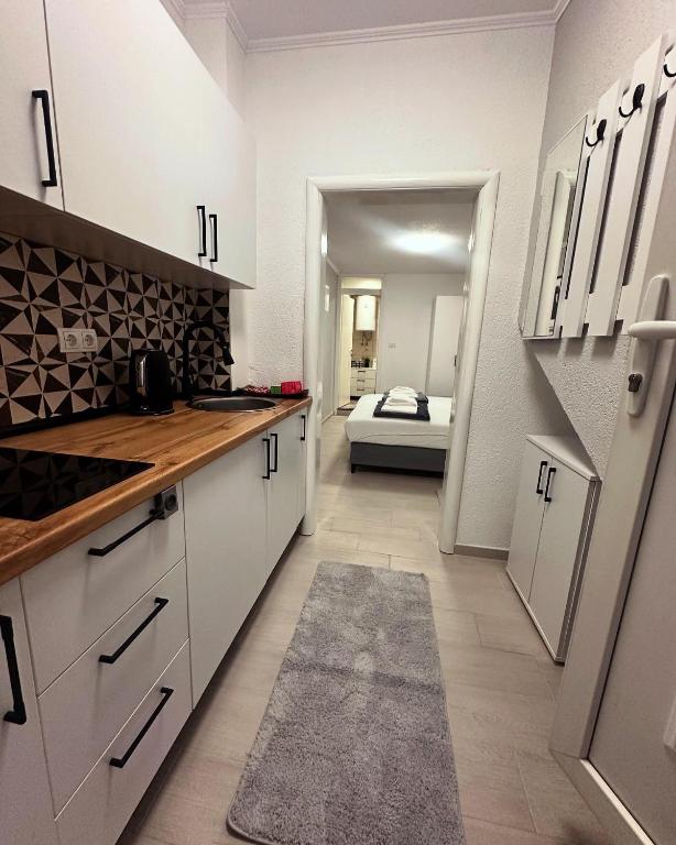 a kitchen with white cabinets and a bed in the background at Mira Apartmani in Mostar