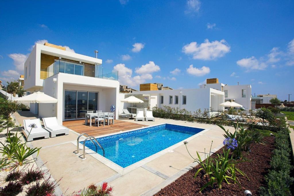 a villa with a swimming pool in front of a house at Luxury Cyprus Villa Turquoise Villa Private Pool Sea View Paphos in Paphos