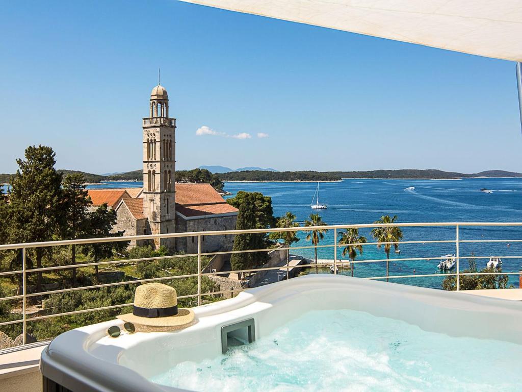 a bath tub with a hat sitting on top of a balcony at Exclusive Hvar Villa 6 Bedrooms Villa Serenity By The Sea Incredible Sea & Monument Views Jacuzzi in Hvar