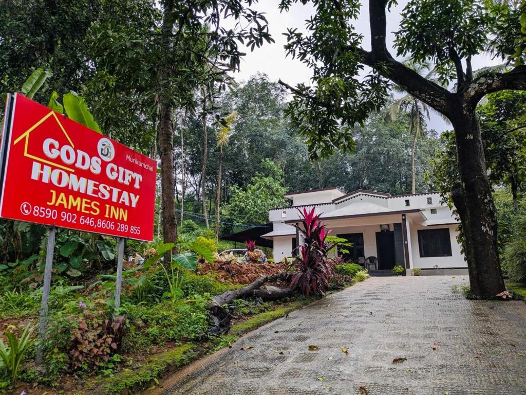 a red sign in front of a house at Gods Gift Homestay James Inn in Kozhikode