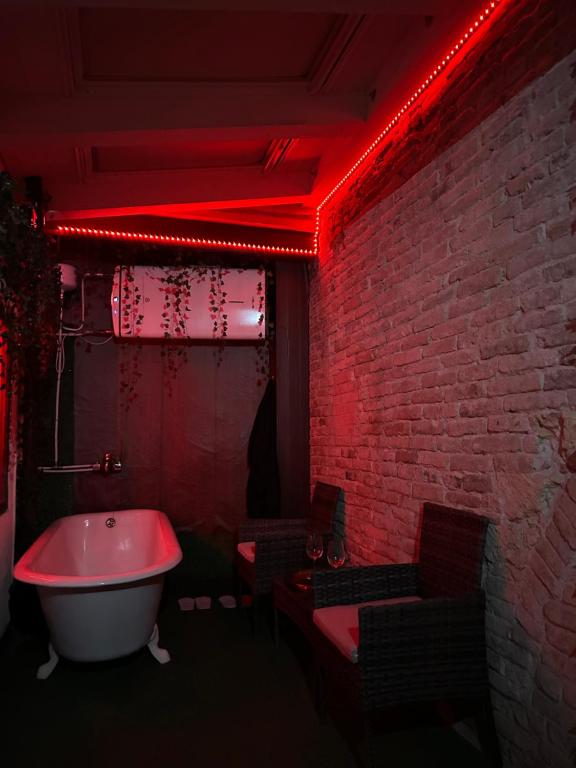 Un baño iluminado en rojo con bañera y pared de ladrillo. en Oasi Del Desiderio, en Verona
