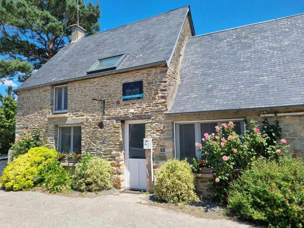a stone house with a white door and some bushes at Au Mont Chez Nous # Jacuzzi & Sauna # in Pontorson