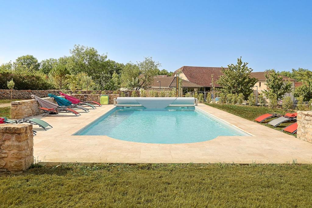 a swimming pool with a bench and chairs in a yard at Grange La Roca Masia in Assier