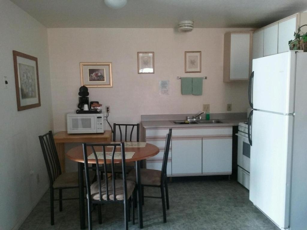a kitchen with a table and a white refrigerator at Bishop Village Motel in Bishop
