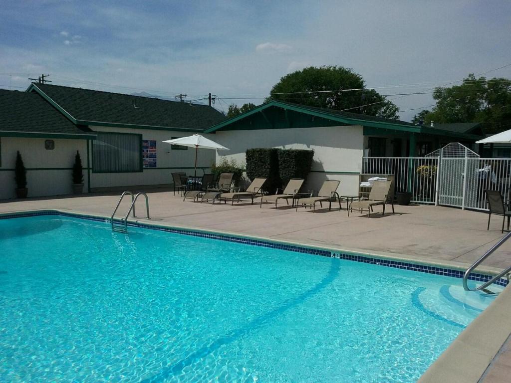 a large blue swimming pool with chairs and umbrellas at Bishop Village Motel in Bishop