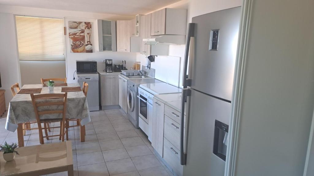 eine Küche mit einem Tisch und einem weißen Kühlschrank in der Unterkunft Ground floor of villa in Brando