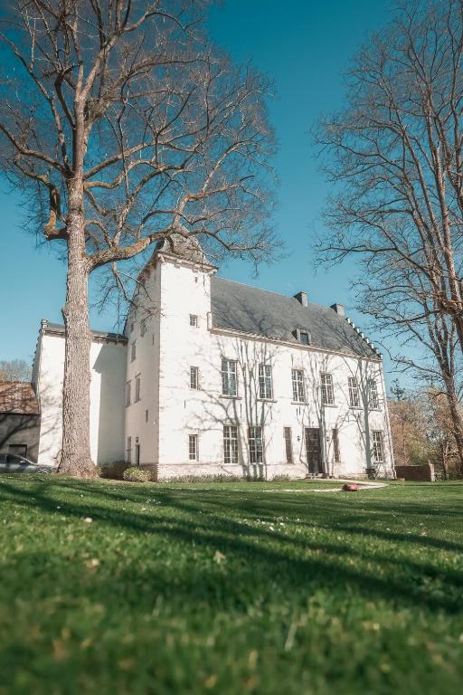a large white house with a tree in the yard at Waterloo Le Manoir de Lasne in Lasne
