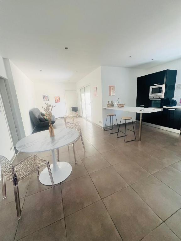 un salon avec une table et des chaises blanches dans l'établissement Charmant T2 en bas de villa avec jardin, à Ajaccio