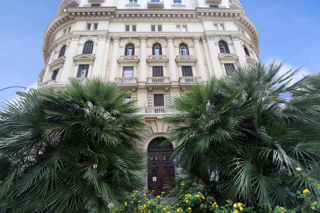 um edifício alto com palmeiras em frente em Piazza Bovio 22 em Nápoles