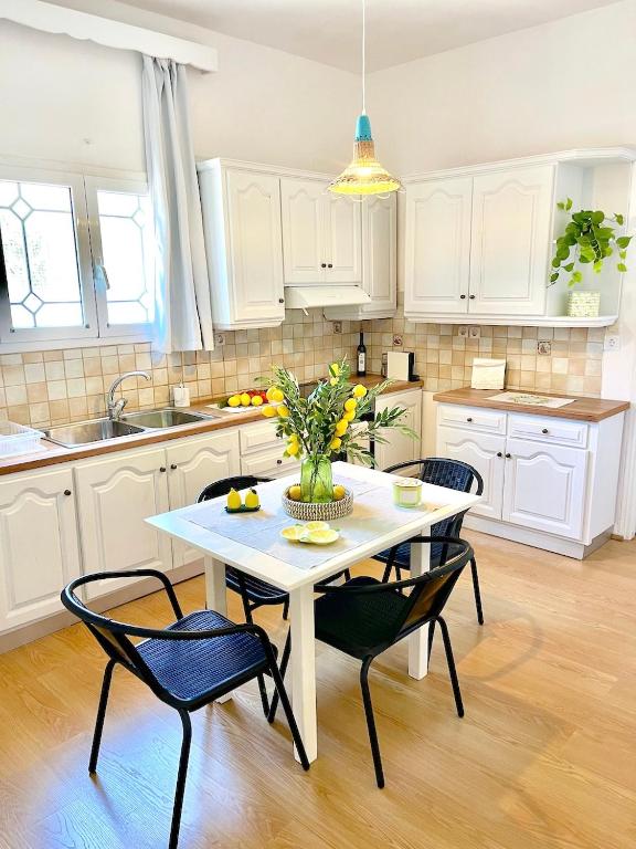 a kitchen with a table with chairs and a vase of flowers at Lemon Tree House, Golden Beach in Chrissi Akti