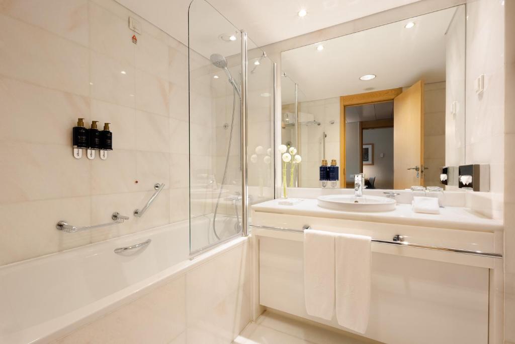 A bright bathroom with a bathtub-shower combination, vanity and large mirror.