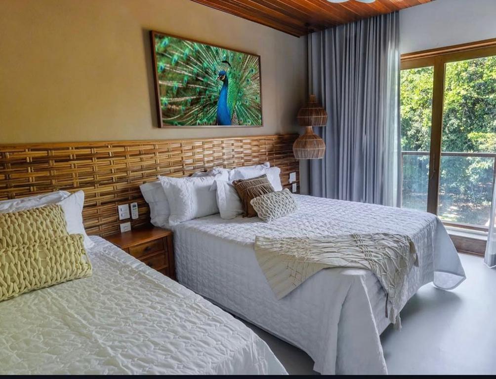 a bedroom with two beds and a painting on the wall at Malhada Jeri in Jericoacoara