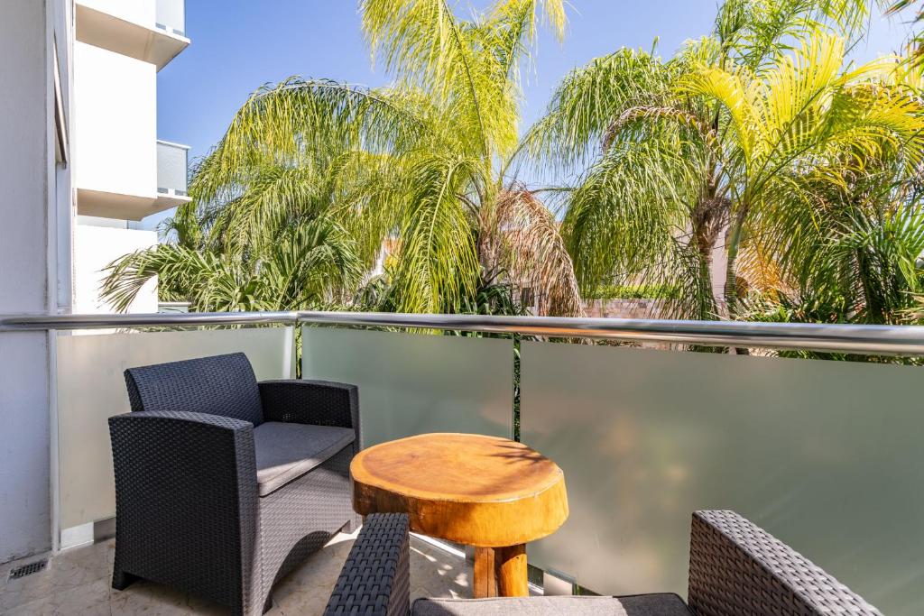 a balcony with chairs and a table and palm trees at Downtown Playa close 5th Av Rooftop Pool in Playa del Carmen