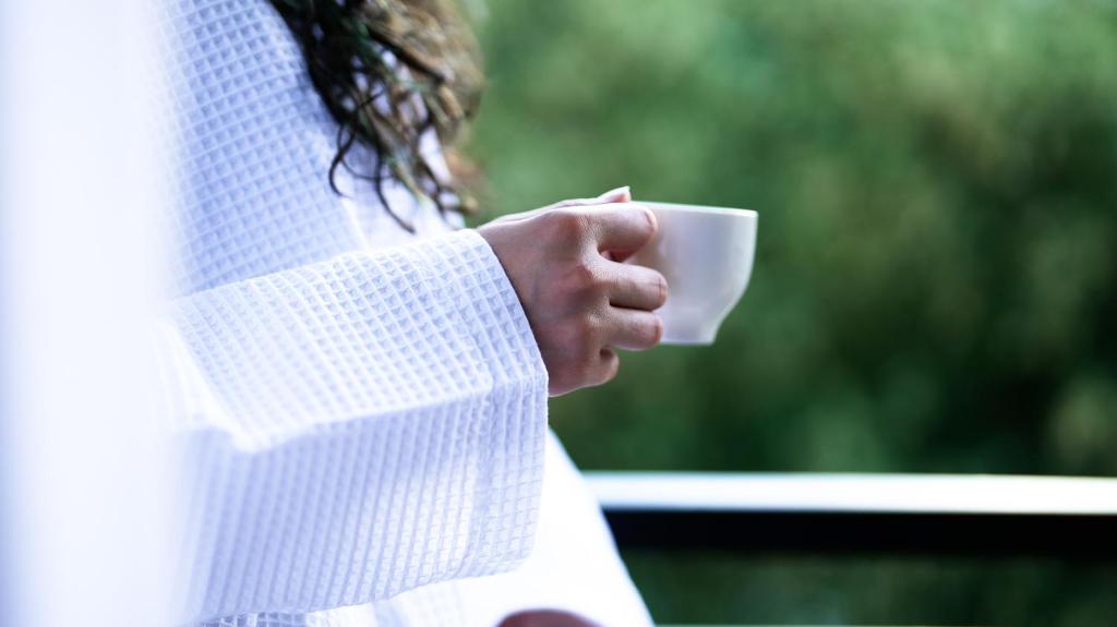 Una mujer sosteniendo una taza blanca en su mano en CNK Hotel By Millennium Group, en Tiflis