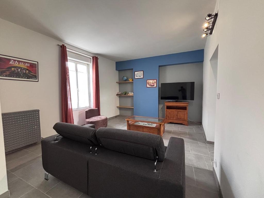 a living room with a couch and a television at La Fléchoise - Maison 3 chambres avec extérieur in La Flèche