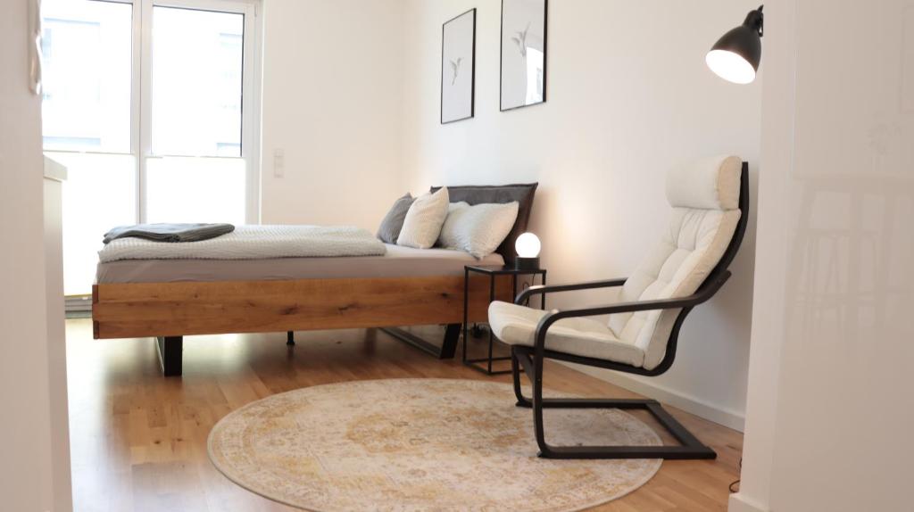 a bedroom with a bed and a chair at Modernes Ein-Zimmer-Apartment in Greifswald