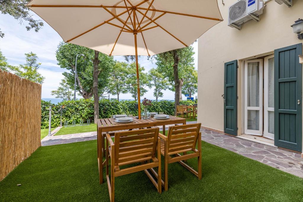a wooden table with two chairs and an umbrella at Casa Orizzonte - Appartamento con vista in Gabicce Mare